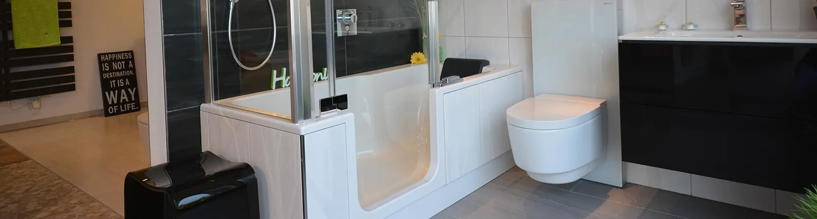 Ein modernes Badezimmer mit integrierter Dusch-Badewanne, die von einer Glasabtrennung umgeben ist. 
