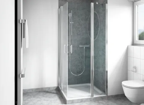 Eine moderne Dusche mit Glasabtrennung steht in der Ecke eines hellen Badezimmers mit grauen Fliesen.