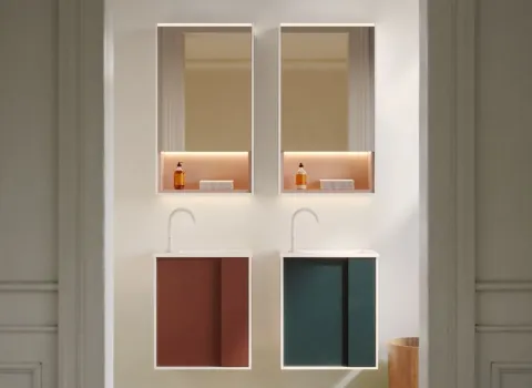 Ein Doppelwaschplatz mit schwebenden Unterschränken zeigt den kreativen Einsatz von Farben und Oberflächen im Bad. Die linke Seite setzt auf einen warmen Terrakottaton, während die rechte Seite mit tiefem Petrolgrün kontrastiert – beide in matter Ausführung.