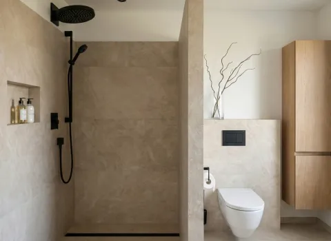 Minimalistisches Badezimmer mit großer Walk-in-Dusche, eleganten schwarzen Armaturen und integriertem Toilettenbereich.