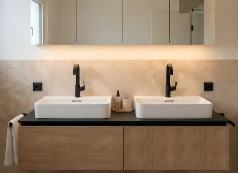 Zeitloses Badezimmer mit zwei rechteckigen Waschbecken auf Holzunterschrank und indirekter Spiegelbeleuchtung.