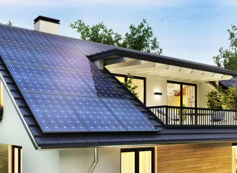 Ein modernes Einfamilienhaus mit Dachterasse und Photovoltaikmodulen.